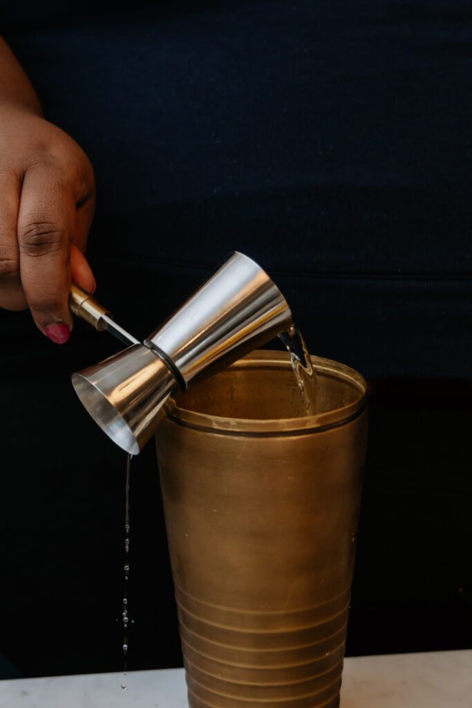 Kandice is adding tequila to a shaker.