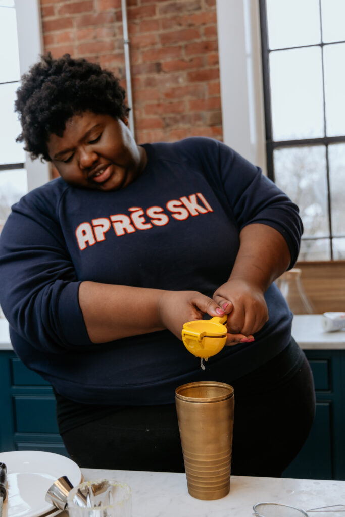 Kandice is squeezing lime juice into a shaker.