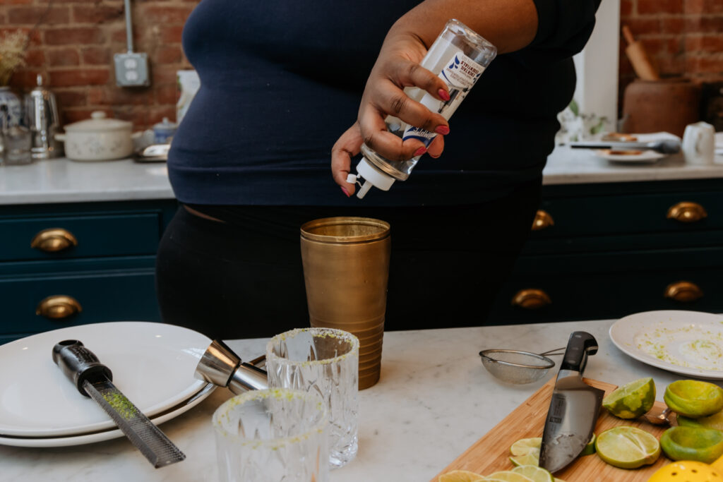 Kandice is adding simple syrup to shaker for classic lime margarita.