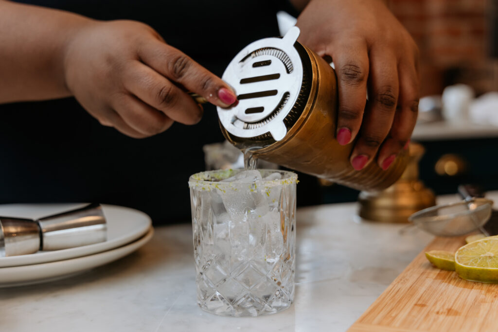 Kandice is straining classic lime margaritas into a glass.