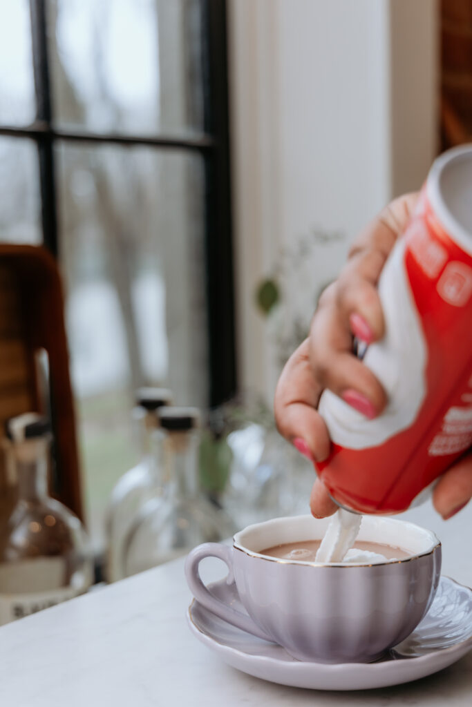 Topping hot chocolate with whipped cream.