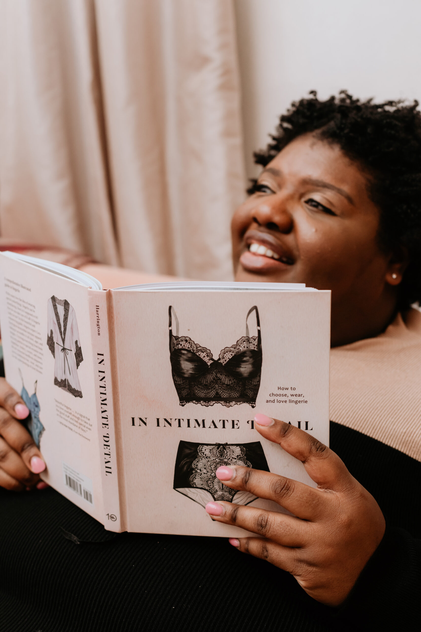 Kandice is sitting on a couch hold up a copy of an intimate detail.