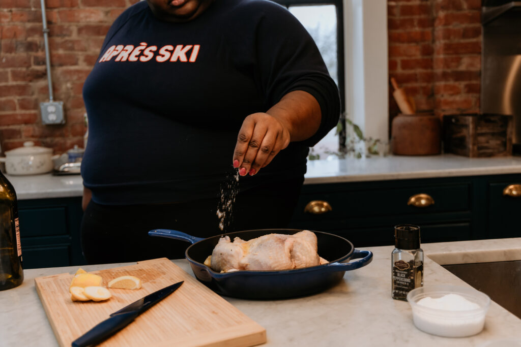 Kandice is salting the chicken.