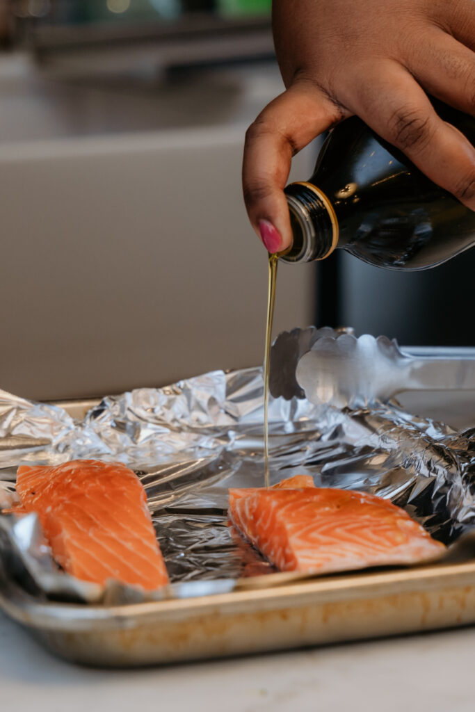 Drizzling olive oil on salmon fillets.