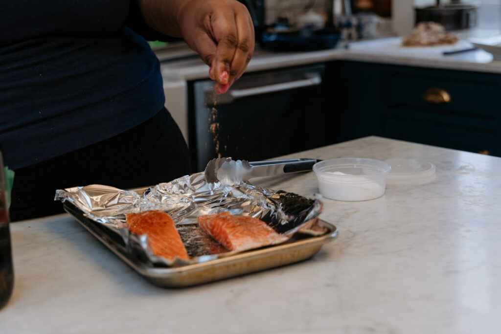 Sprinkling spice mixture on salmon fillets.