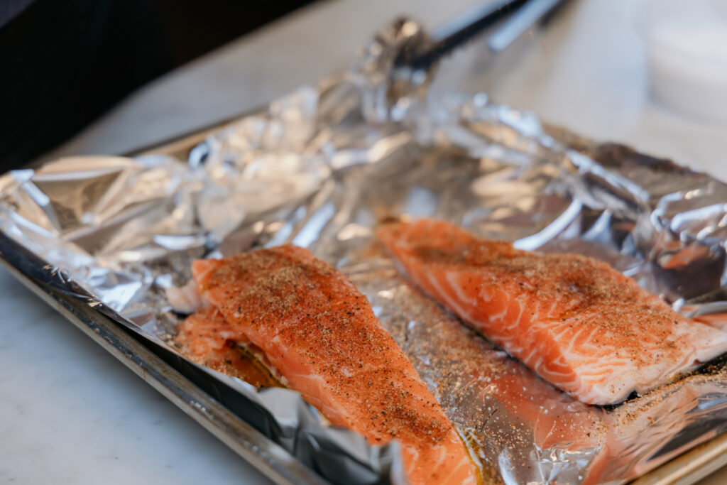 Salmon is on a foil lined sheet pan covered in spice mixture.