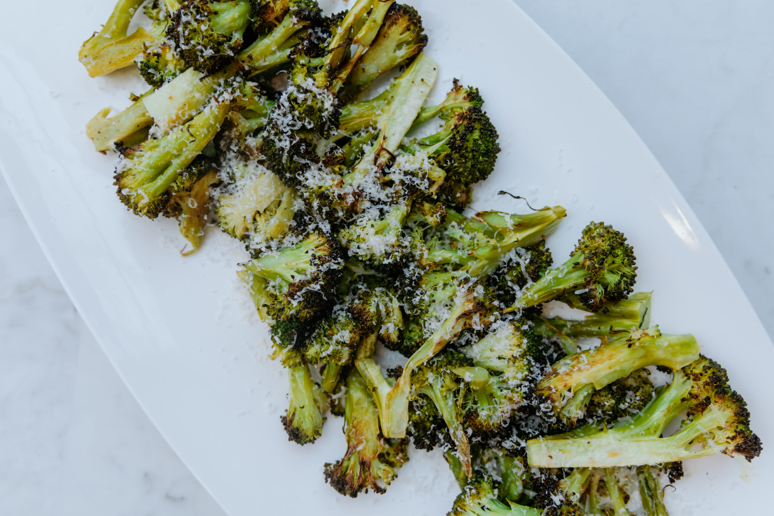 A platter of slow roasted broccoli with lemon and cheese.