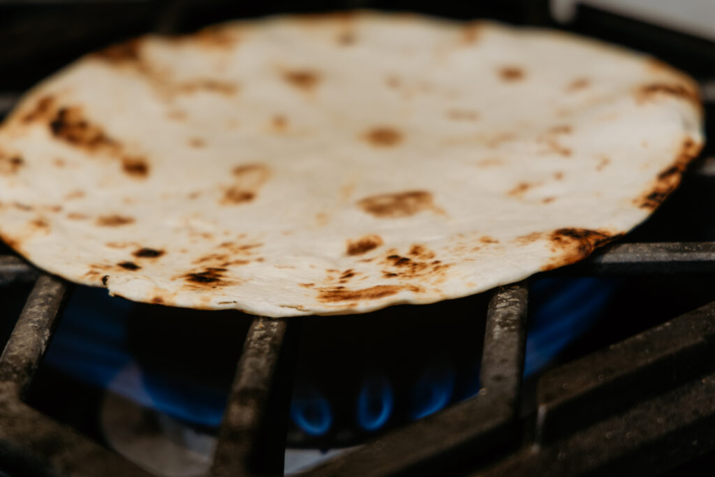 Tortilla being toasted over open flame.