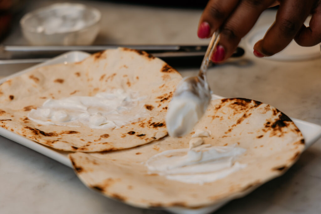 Spreading lime crema on bottom of tortilla.