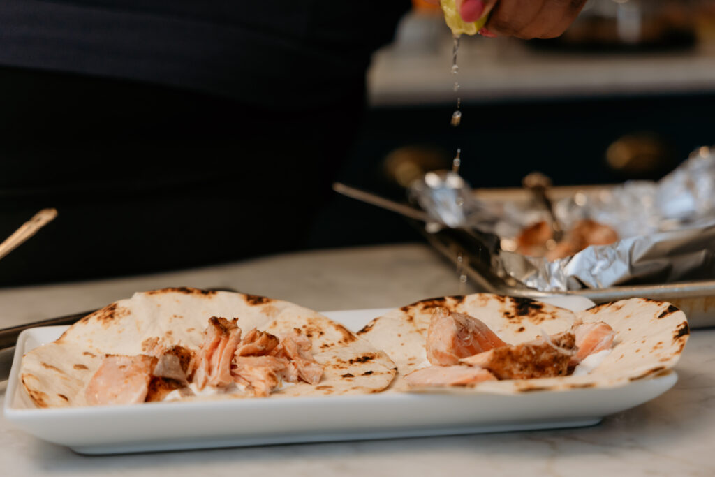 Placing salmon chunks on tortillas. 