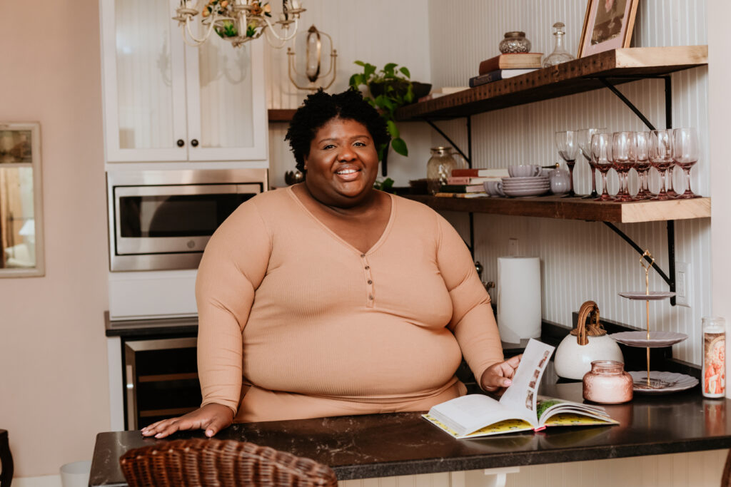 Kandice is standing in a kitchenette wearing a monochrome outfit,