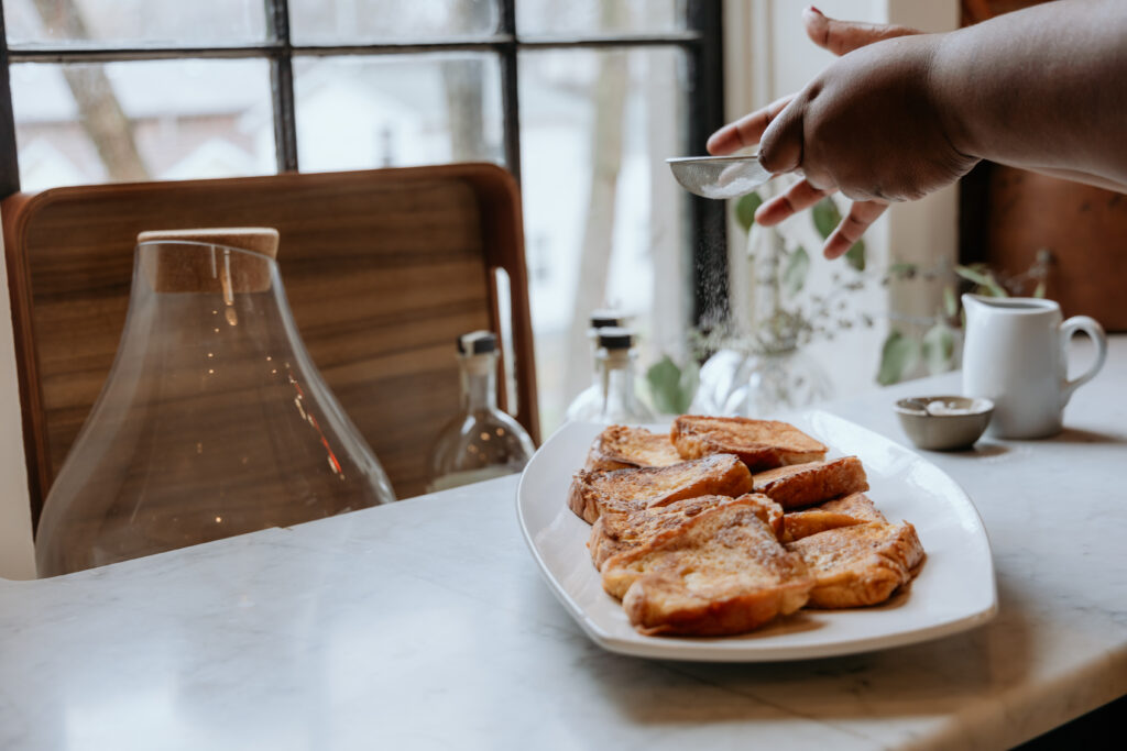 Dusting french toast with powdered sugar.