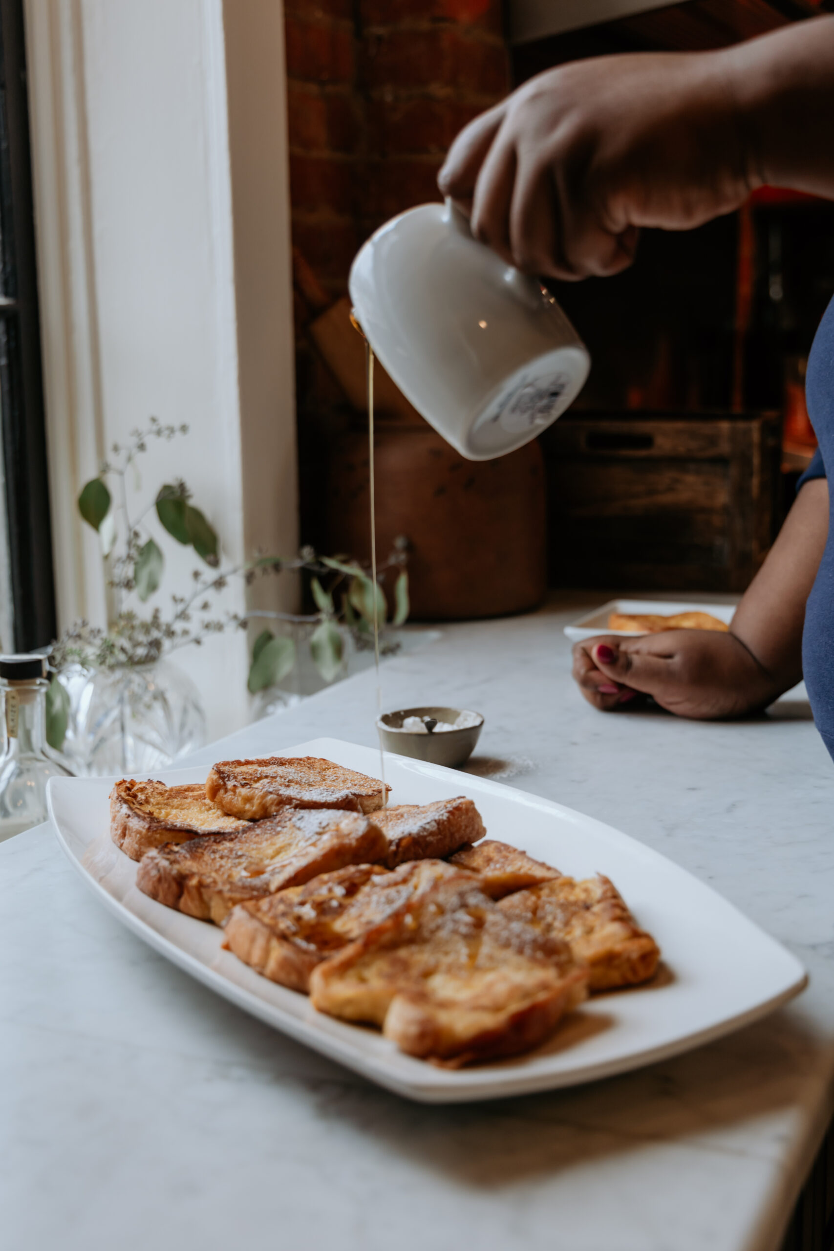 Easy Brioche French Toast recipe being drizzled with maple syrup.