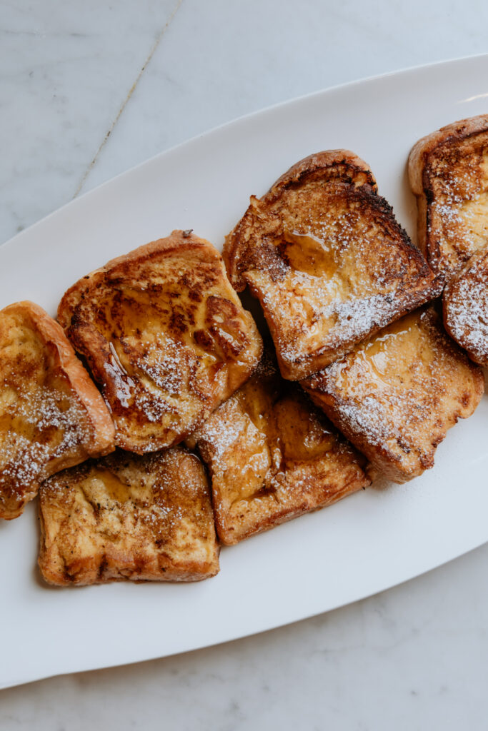 Easy Brioche french toast on a platter drizzled with maple syrup.