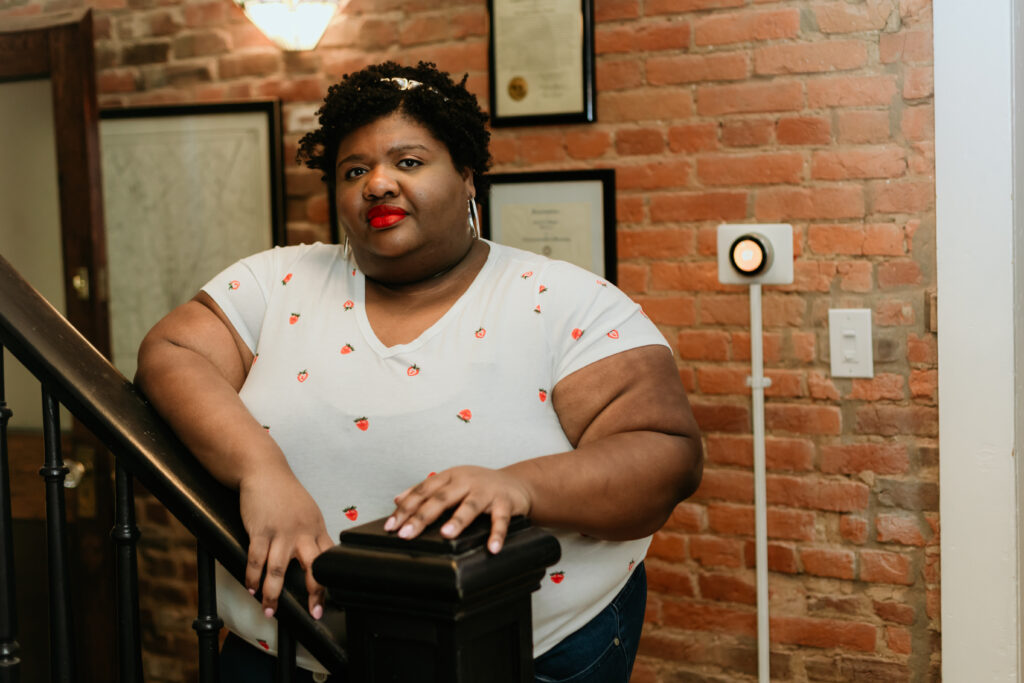 Kandice is leaning over a banister in a fun spring t-shirt.