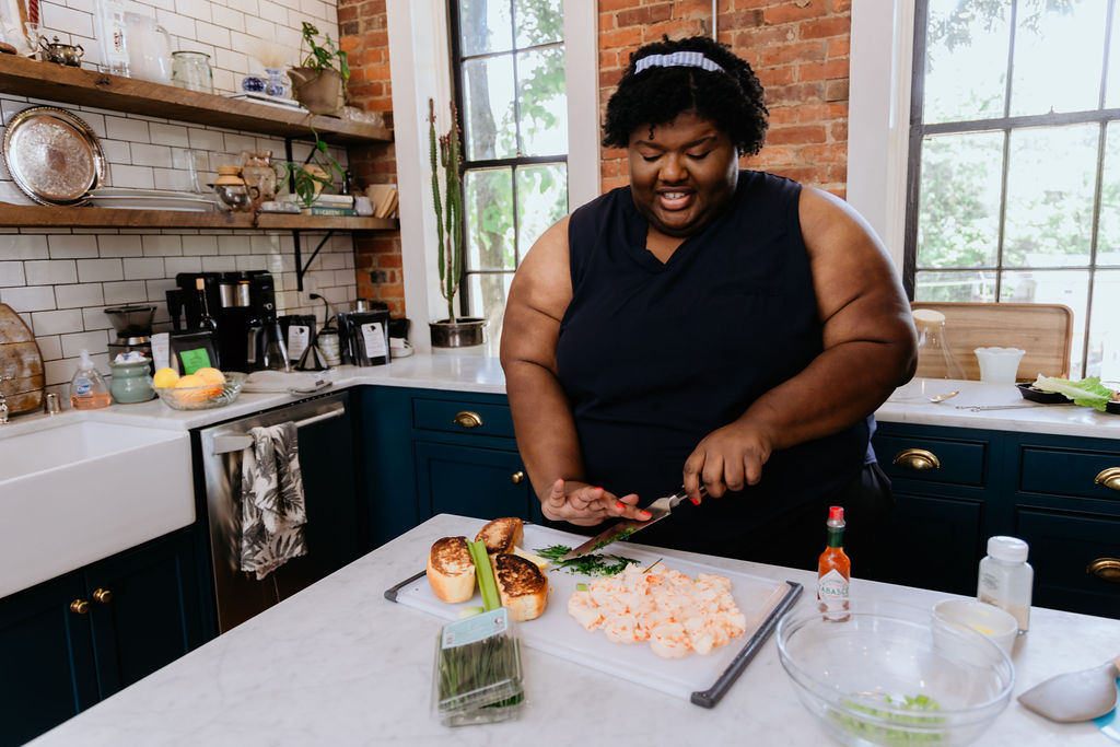 Kandice is chopping up herbs and celery for shrimp rolls.