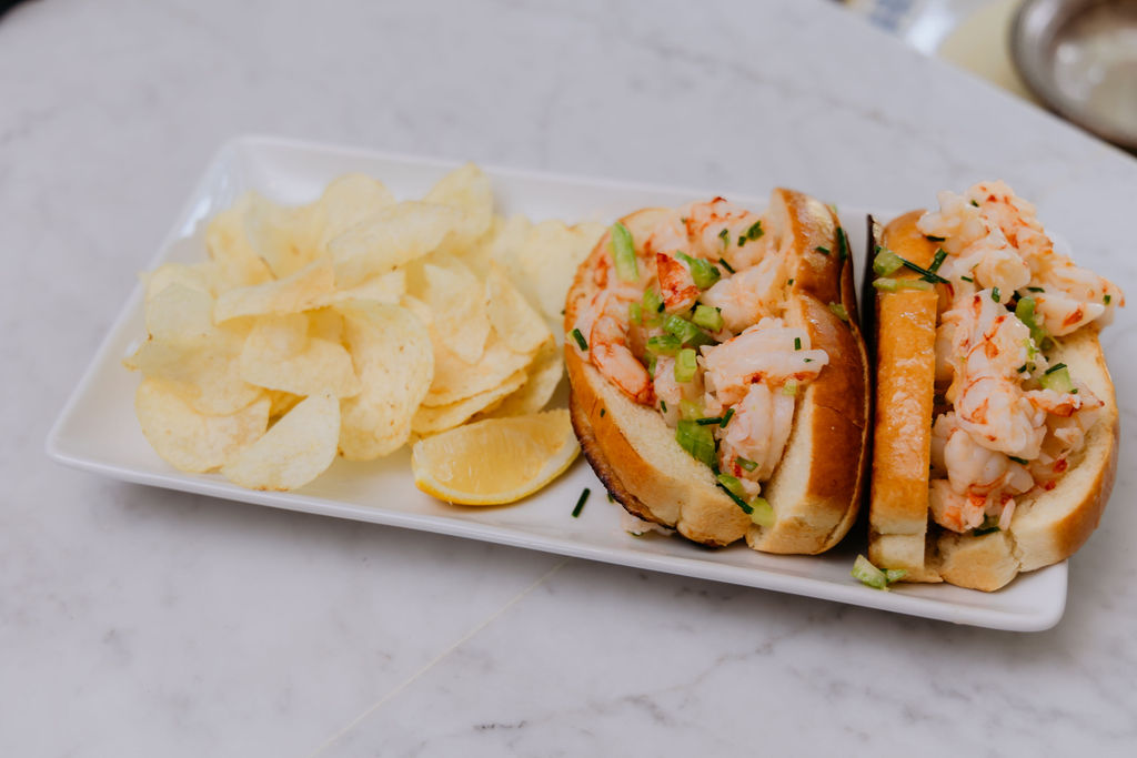 Shrimp roll on a plate with chips.