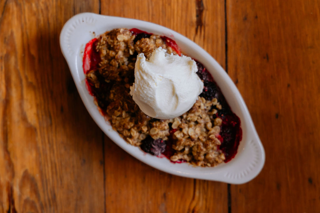 Mixed berry crisp with a scoop of vanilla ice cream on top.