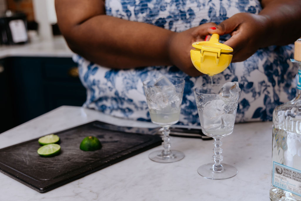 Kandice is squeezing lime juice into glasses.