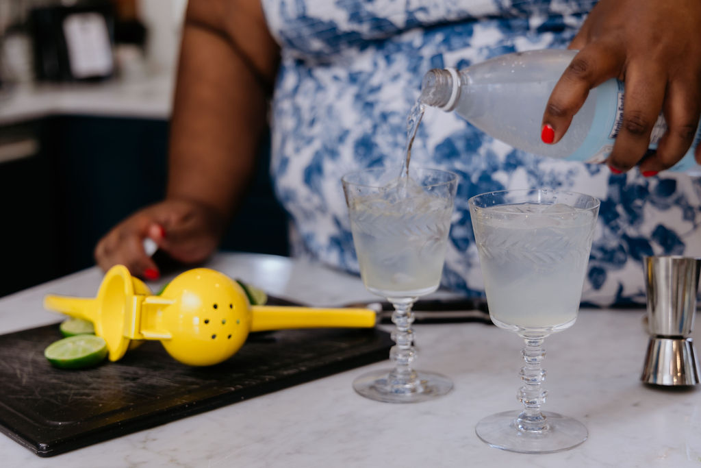 Kandice is pouring sparkling water into cocktail.