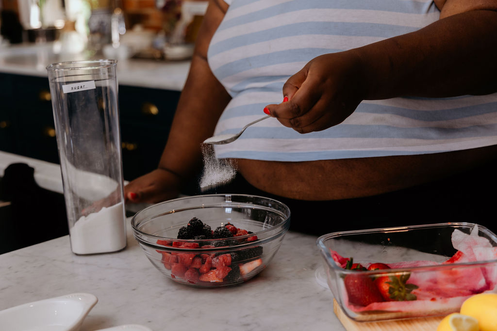 Kandice is sprinkling sugar into berries.