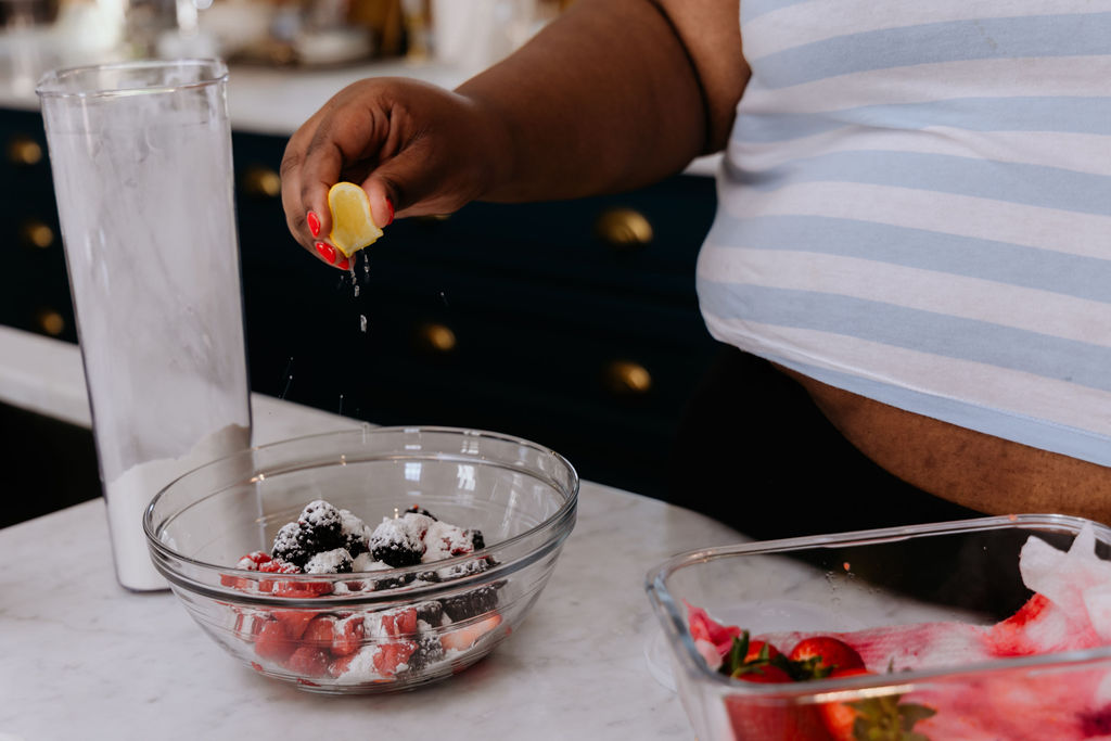 Kandice is squeezing lemon juice over berry mixture.