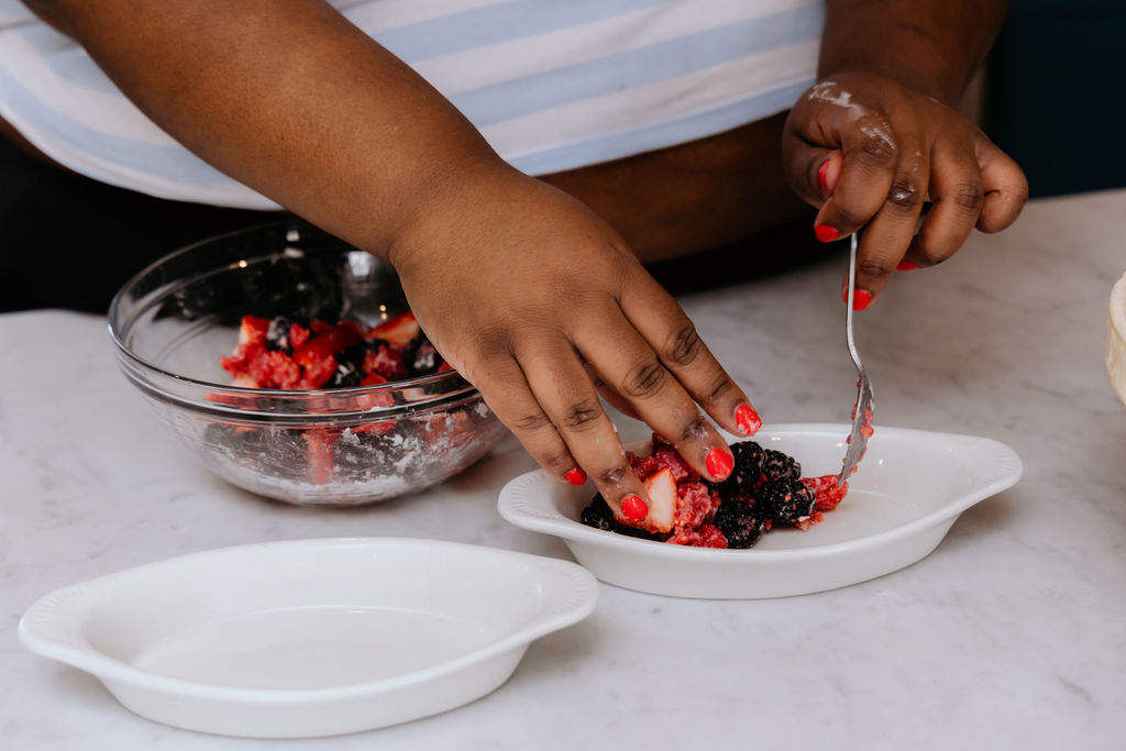 Mixed fruit is being placed in au gratin dish,