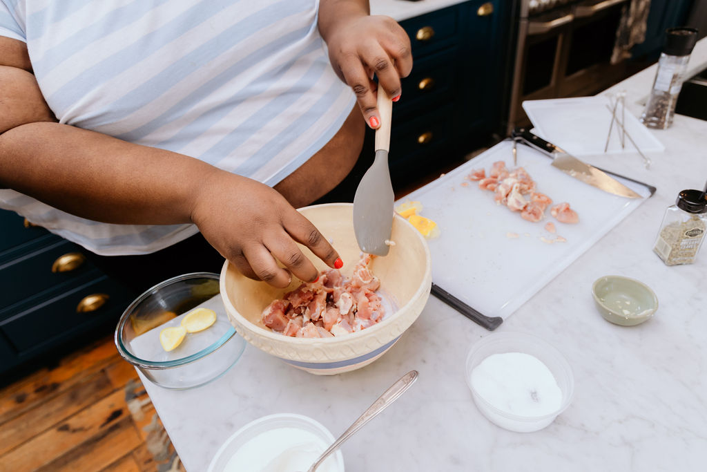 Kandice is mixing chicken into yogurt marinade for chicken gyro skewers.