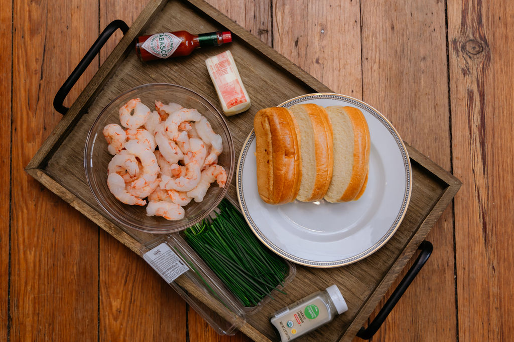 A wooden tray with the ingredients for shrimp rolls laid out.