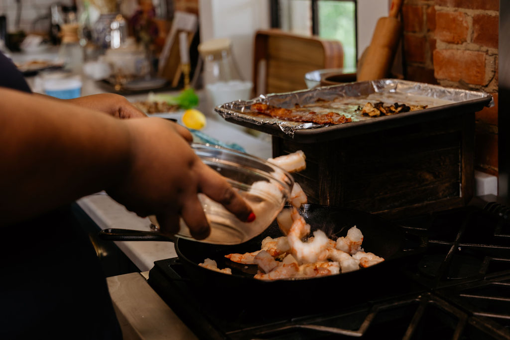 Kandice is pouring shrimp into a skillet.