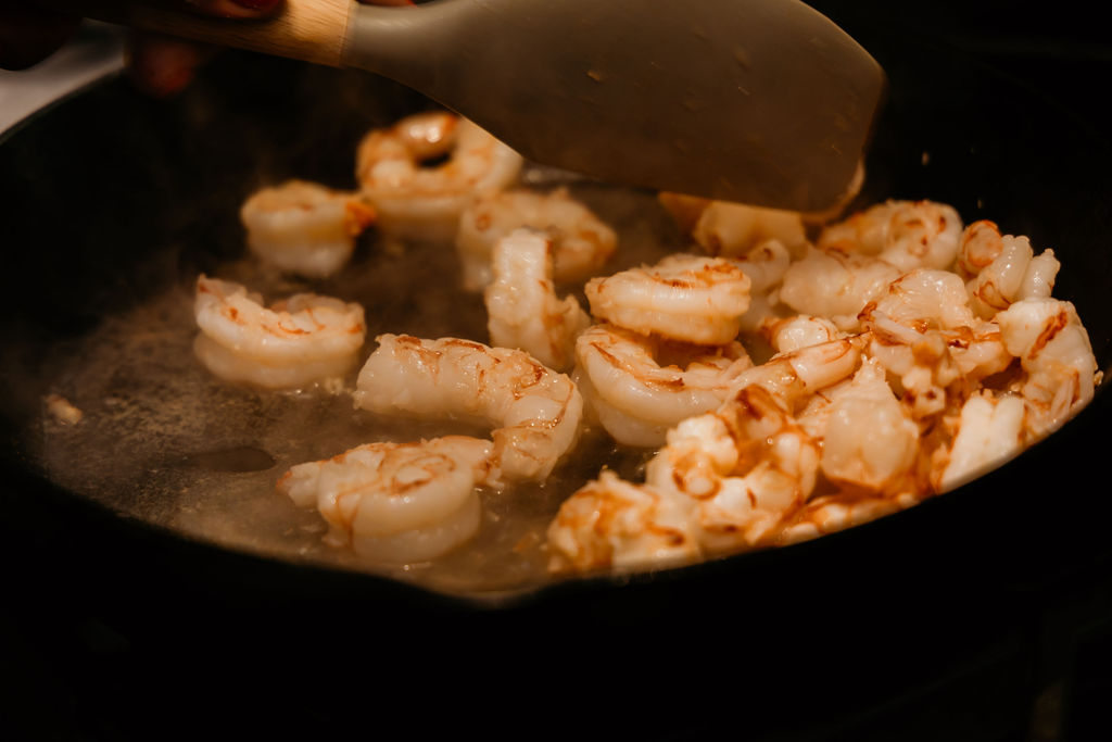 Shrimp for shrimp rolls being sautéed in a skillet.