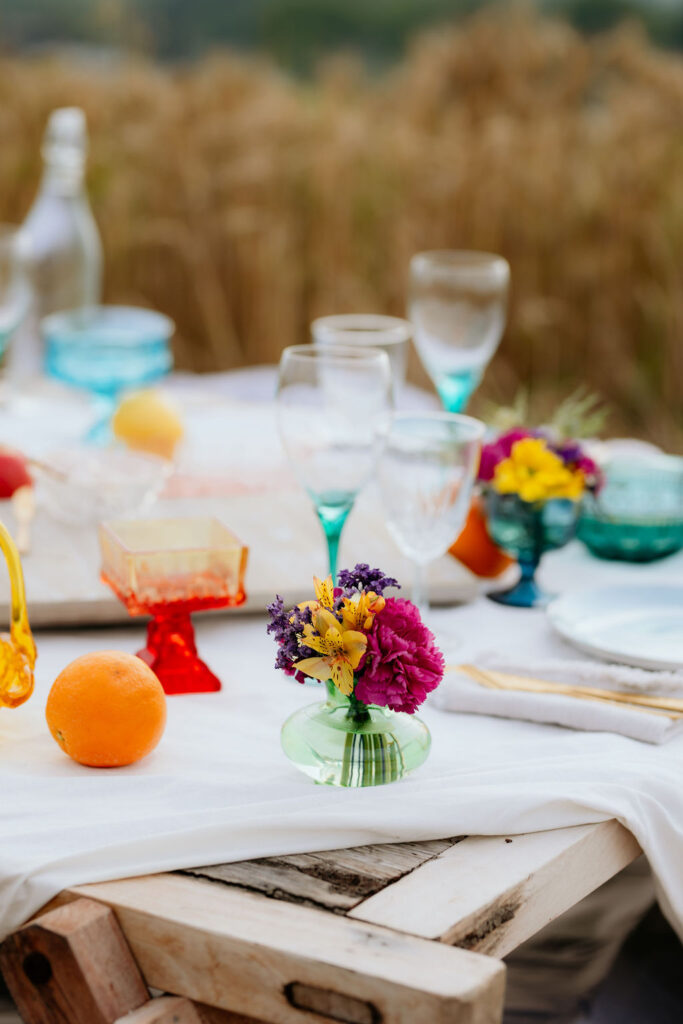 A summer picnic setup with wine glasses and fresh flowers.