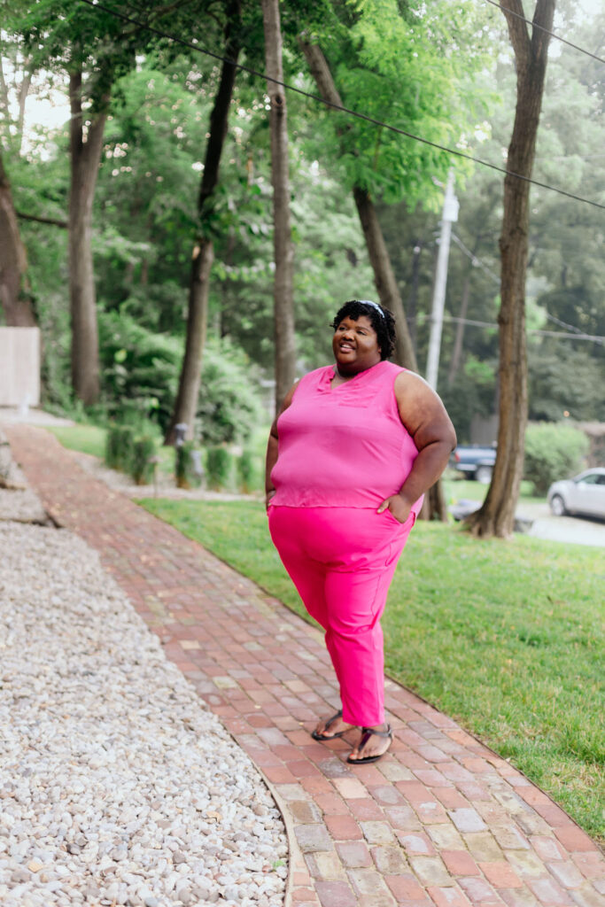 Kandice is standing on a walkway, wearing Barbie Pink