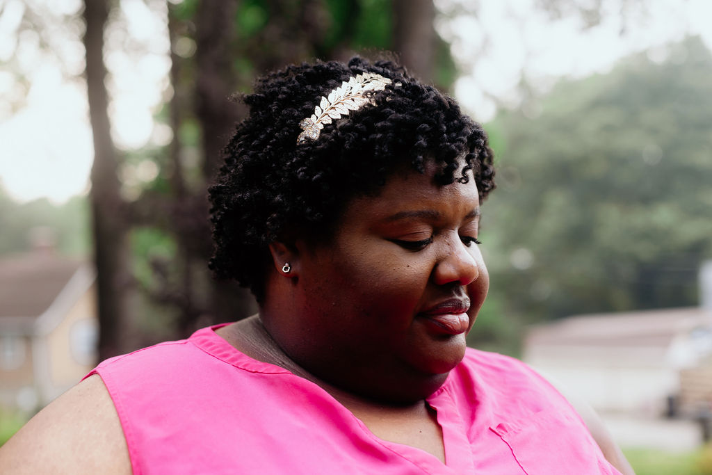 A close up of Kandice wearing a gold headband,