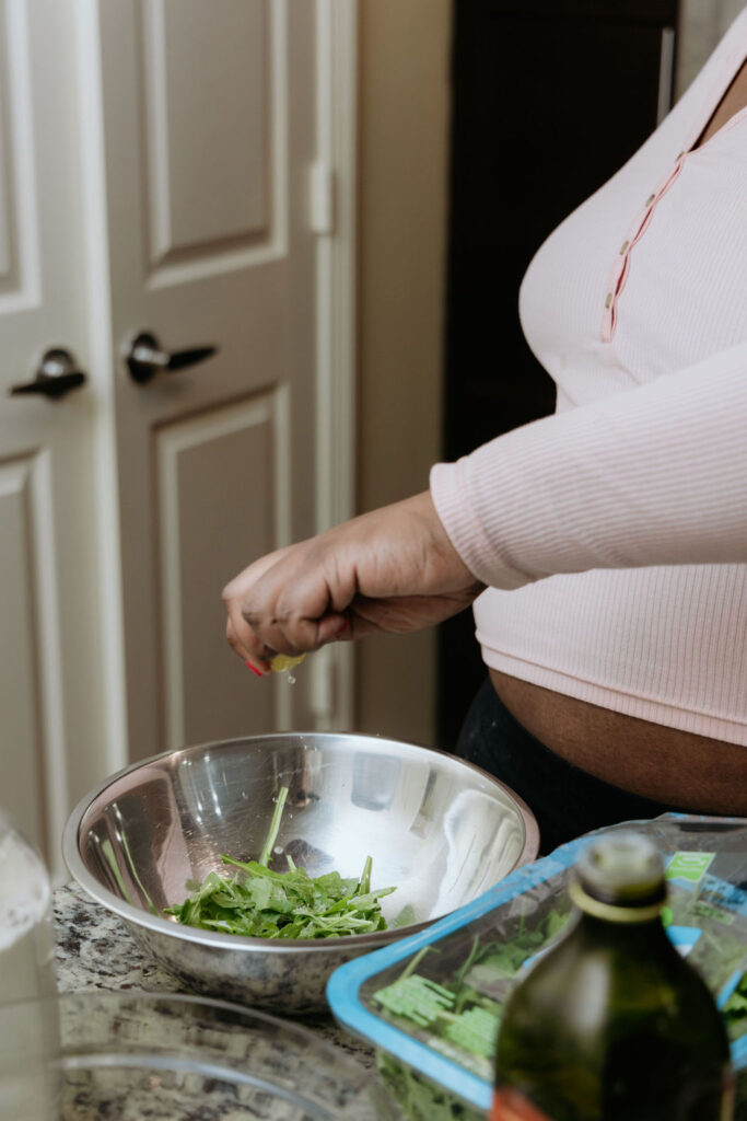 Kandice is squeezing lemon juice on arugula.