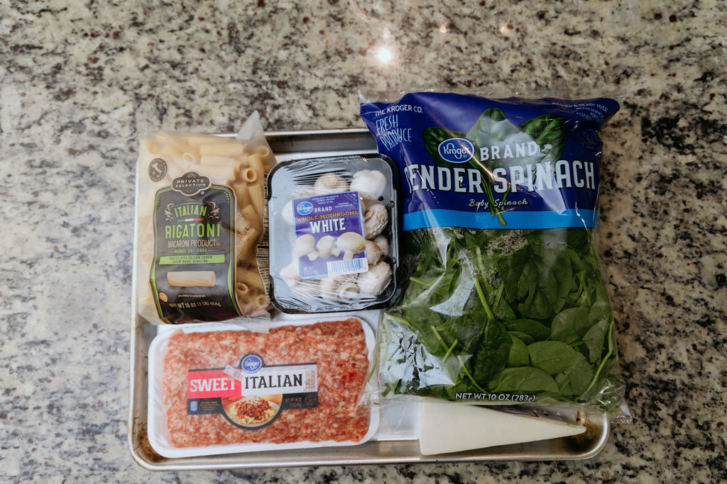 Flat lay of ingredients for sausage spinach and mushroom pasta.