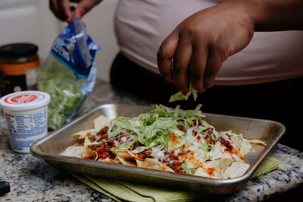 Kandice is adding lettuce to nachos.