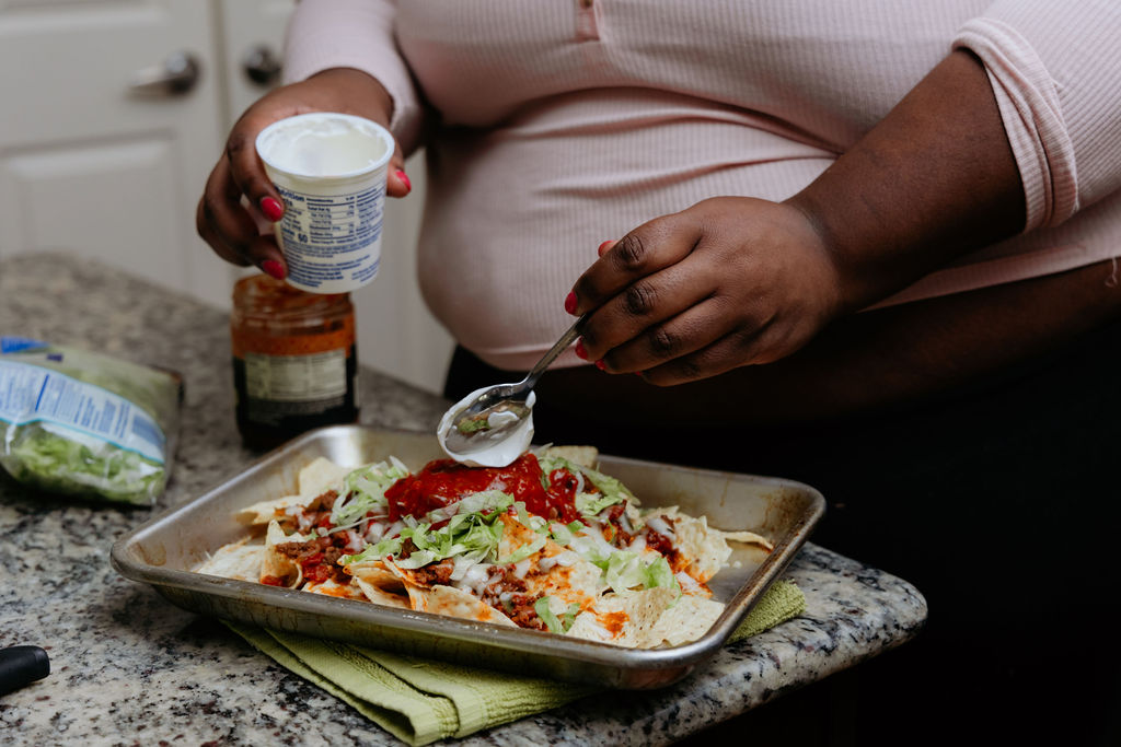 Kandice is adding sour cream to nachos.