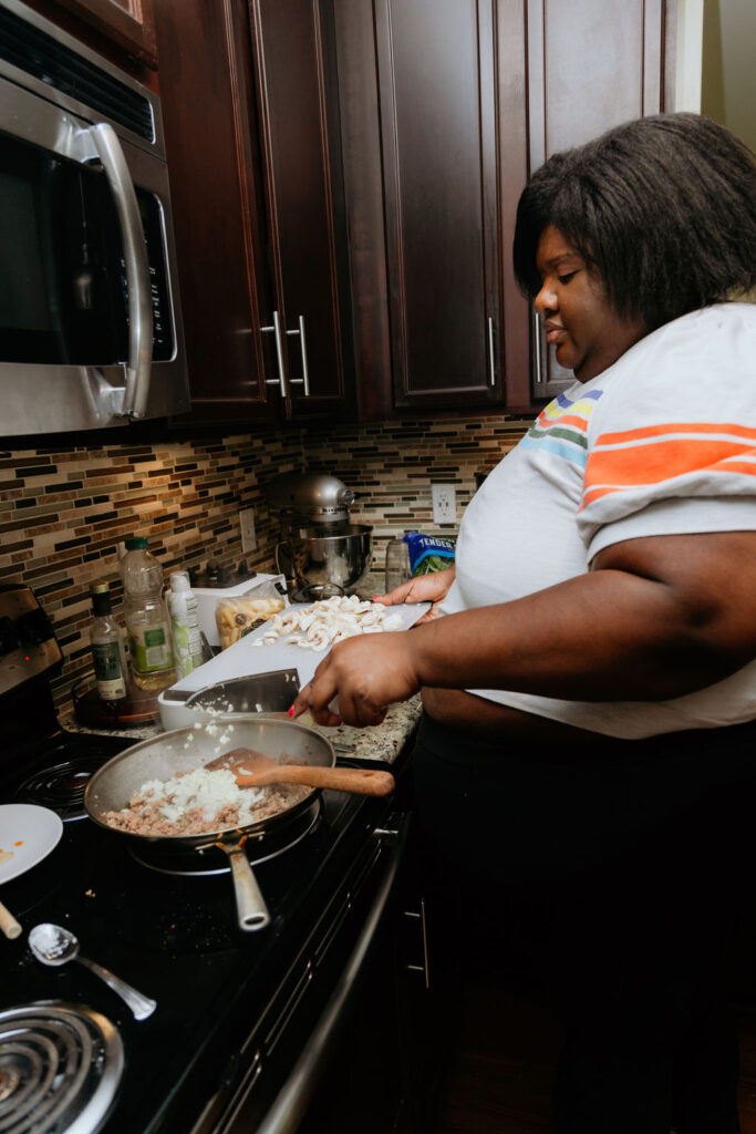 Kandice is adding onions and garlic to pan.