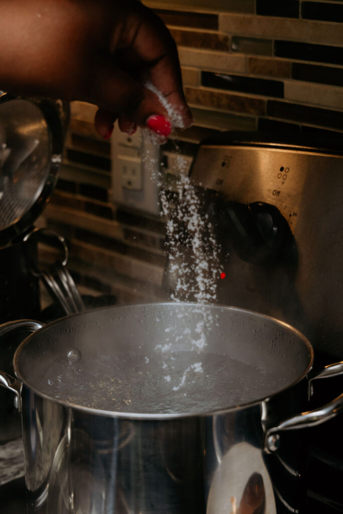 Kandice is salting pasta water.