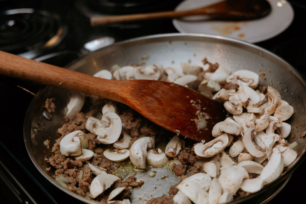 kandice is stirring mushrooms in a pan.