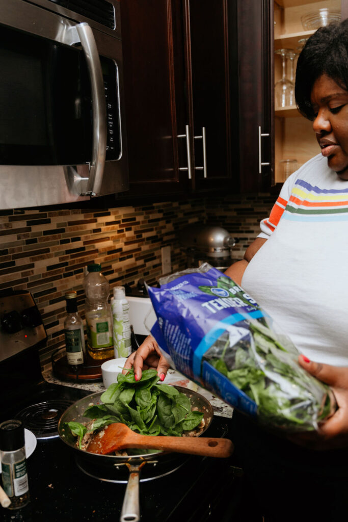 Kandice is adding spinach to pan.