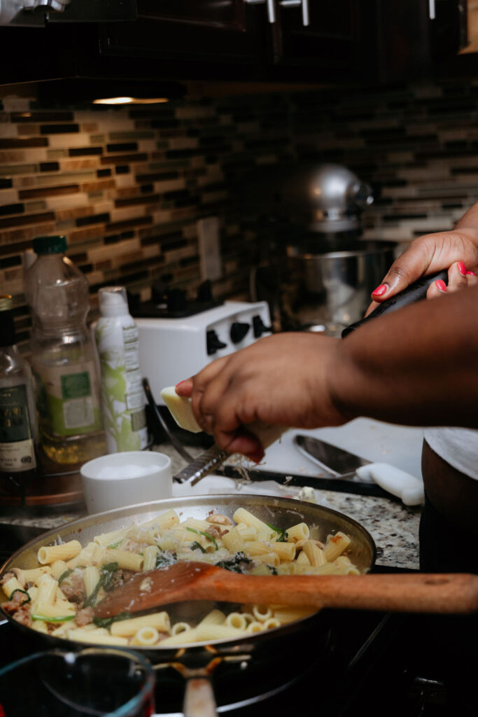 Kandice is grating cheese into pasta.