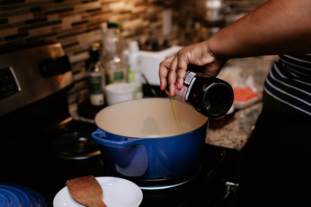 Kandice is adding olive oil to pot.