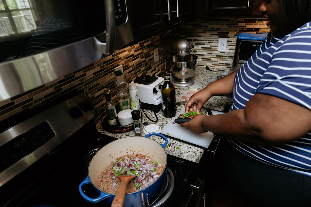 Kandice is adding chopped veggies to pot.