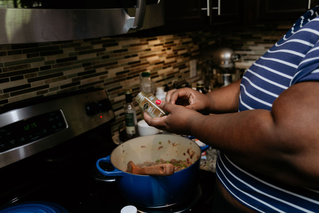 Kandice is adding spices to chili.