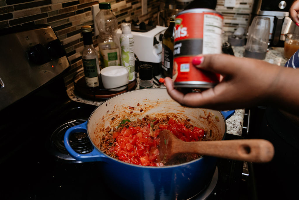 Kandice is adding fire roasted tomatoes to pot/