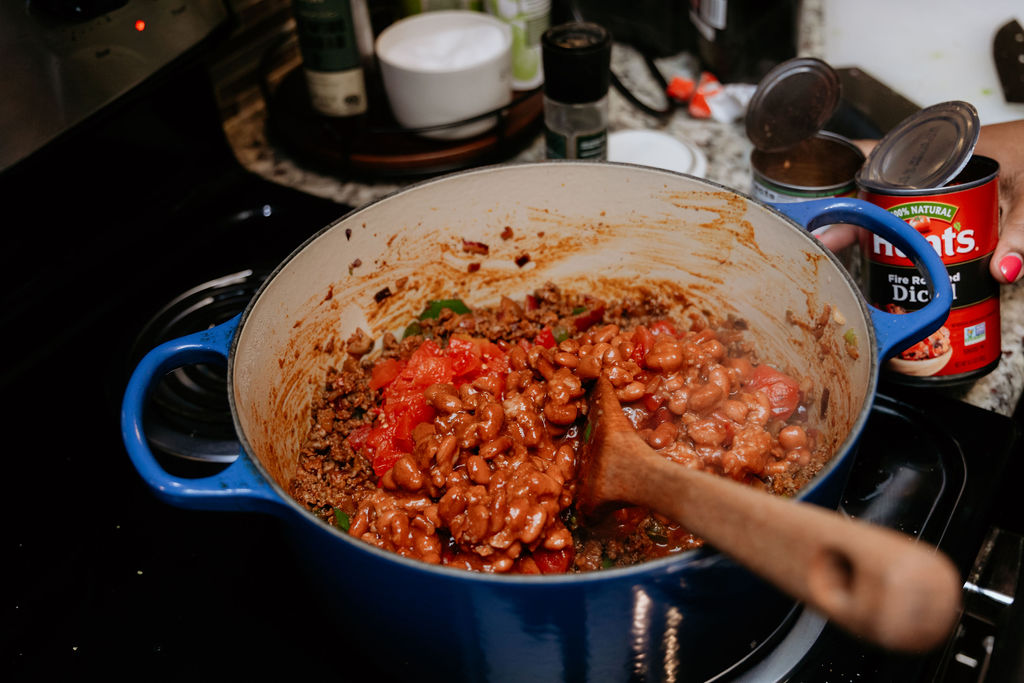 Kandice is adding chili beans to pot.